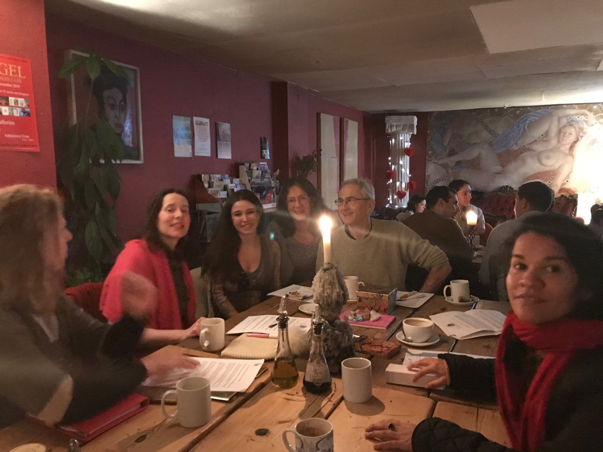 Emily with a group of creative people around a candlelit café table, sharing ideas over coffee